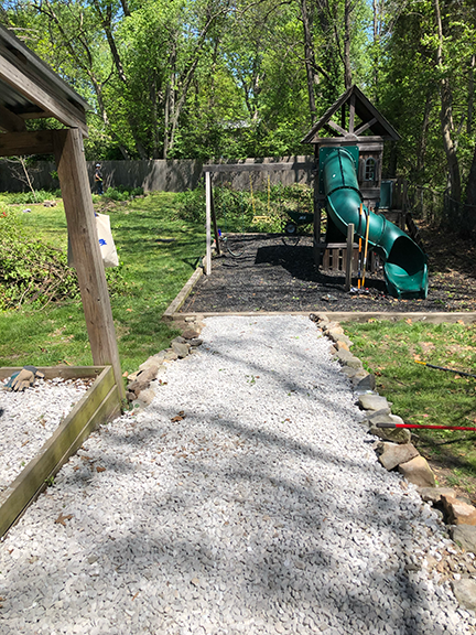 Picture of a gravel walkway leading to playground equipment with a large green slide