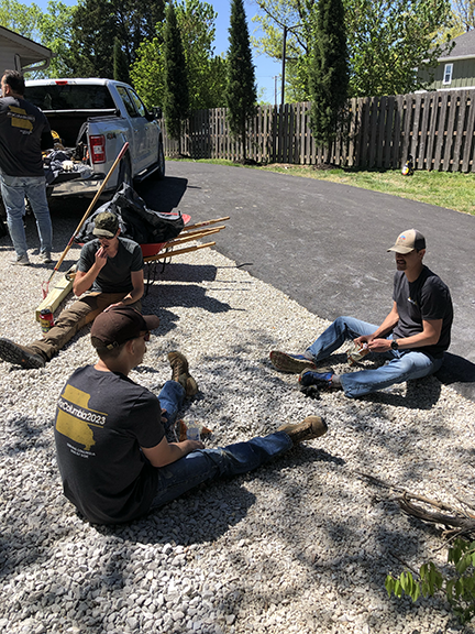 Three men take a rest on a gravel driveway